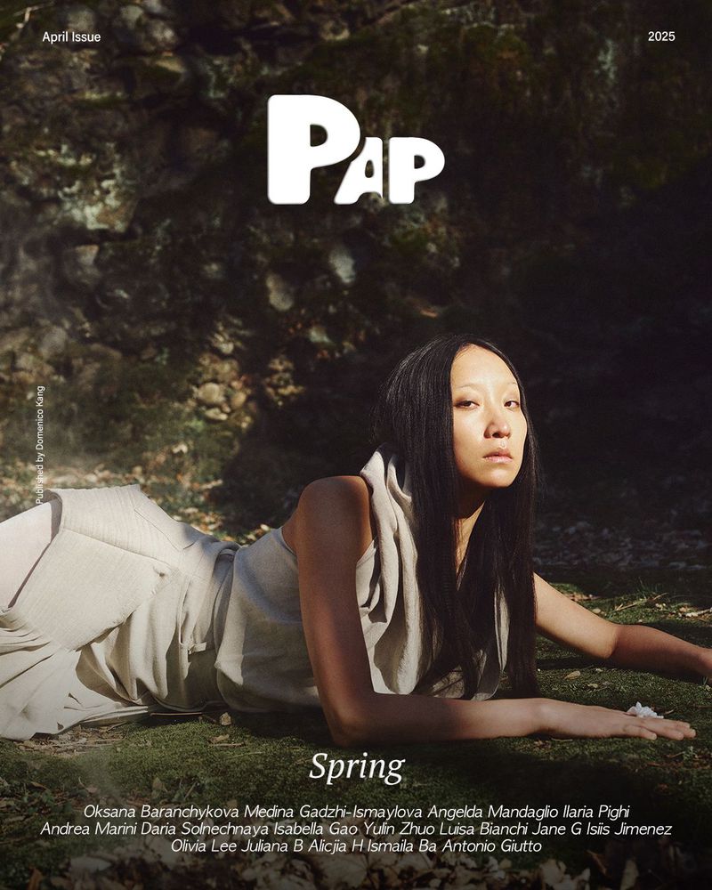 Model with long dark hair lying on mossy ground wearing a beige sleeveless top for PAP Magazine