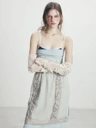 Model in pale blue layered dress wearing sheer opera gloves with white appliqué against a seamless white background.