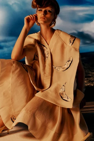 Model Aylah Peterson wearing a cream patterned vest and skirt set against an outdoor sky background