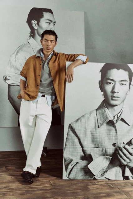 A stylish Asian male model poses indoors wearing casual attire with photo-based backdrops featuring his image in a fashion editorial style.