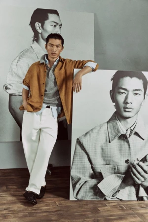 A stylish Asian male model poses indoors wearing casual attire with photo-based backdrops featuring his image in a fashion editorial style.