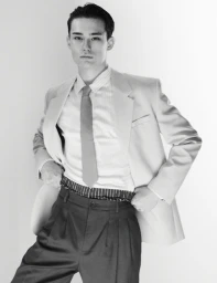 Monochrome fashion portrait of Alex Schlab wearing a tailored blazer and tie for HERO Magazine.