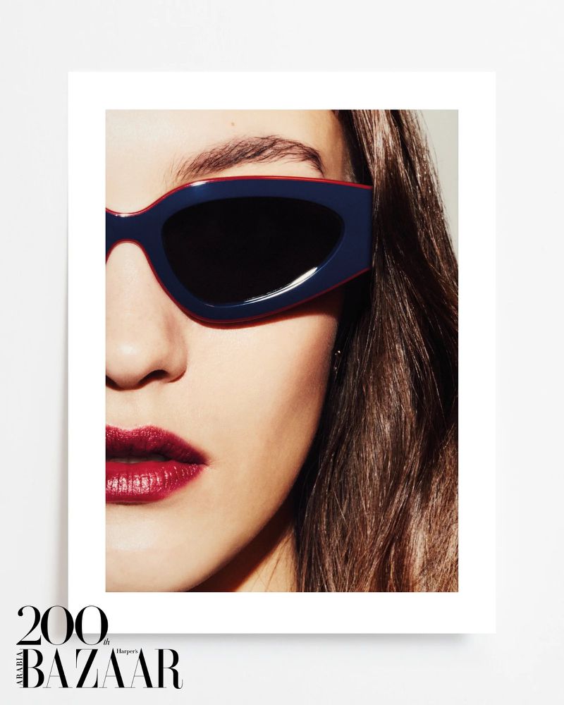 Close-up portrait of a woman wearing navy-and-red sunglasses with dark lenses and bright red lipstick, showcasing beauty and fashion.