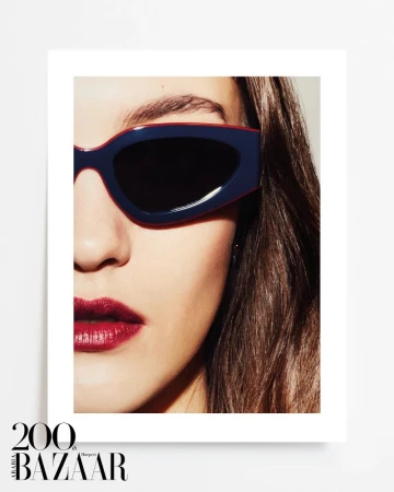 Close-up portrait of a woman wearing navy-and-red sunglasses with dark lenses and bright red lipstick, showcasing beauty and fashion.