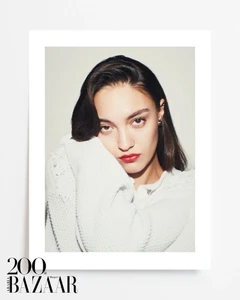 Portrait of a model wearing a white knit cardigan with bold red lipstick against a plain white studio background.