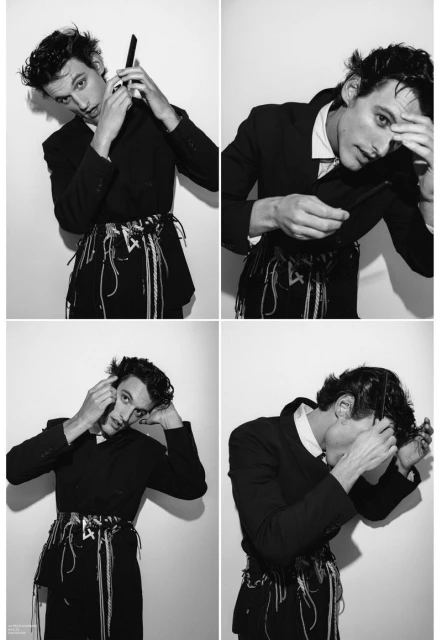 Black and white fashion shot of a man in a suit, combing his hair in a studio setting. Editorial style with a clean backdrop.