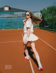 Female tennis player in white athletic skirt and top holding a racket on a clay court for Elle Bulgaria editorial project