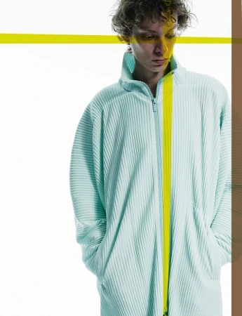 A person wearing a light turquoise, zip-up, ribbed jacket with a vertical neon yellow stripe, against a white background with yellow accents.