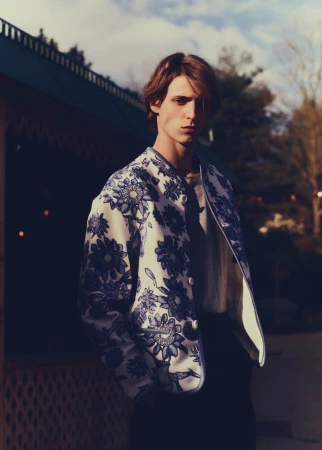 Model wearing a blue and white patterned floral jacket outdoors during twilight for Grazia International