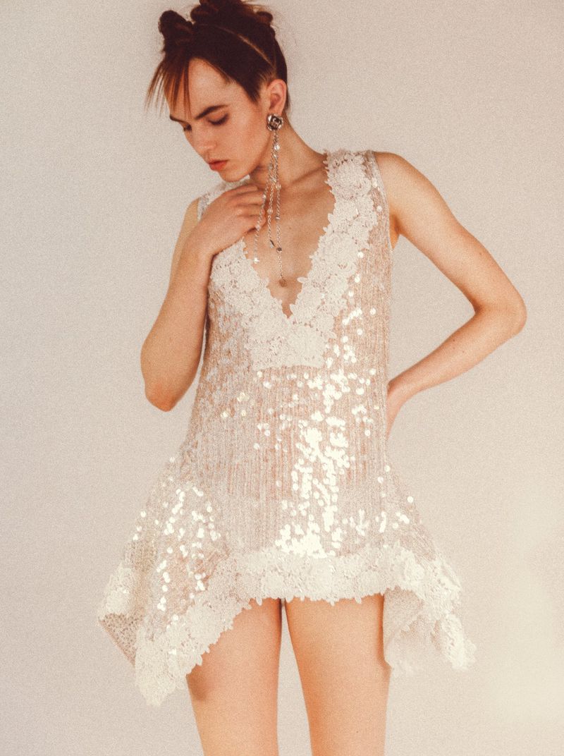 Model wearing a sequined white dress with lace trim standing against a seamless background for WRPD Magazine