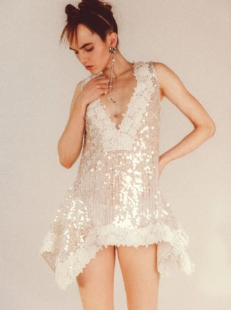 Model wearing a sequined white dress with lace trim standing against a seamless background for WRPD Magazine