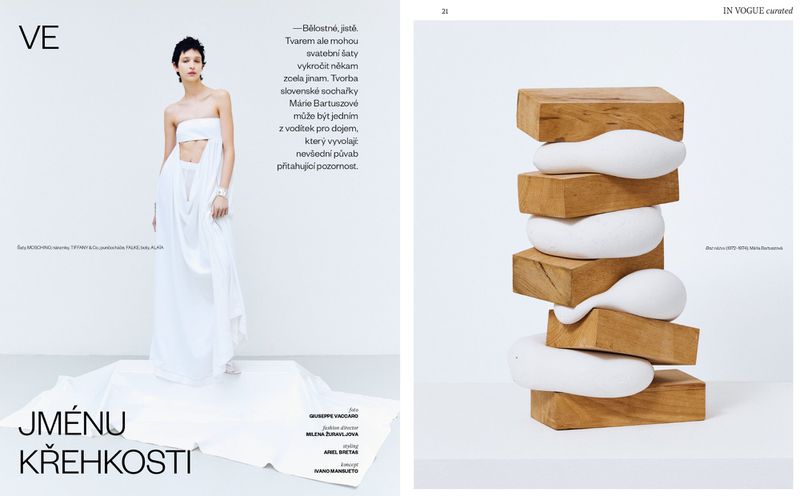Fashion editorial featuring a woman in a white dress with a modern sculpture made of wood and white filler on a white background.