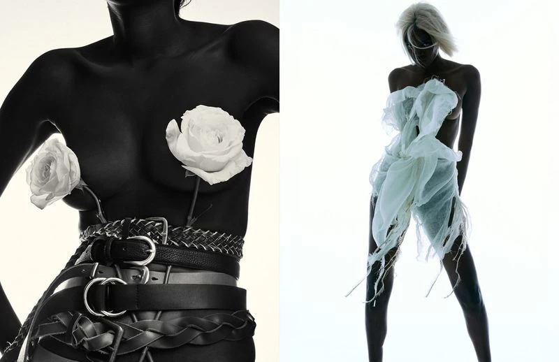 Two women strike poses in a studio setting; one wears belts and roses, while the other is adorned with sheer white fabric.