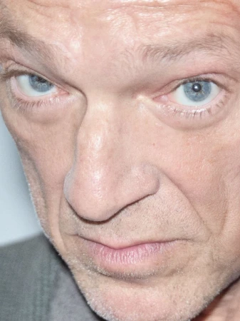 Close up portrait of actor Vincent Cassel looking intensely at the camera with blue eyes