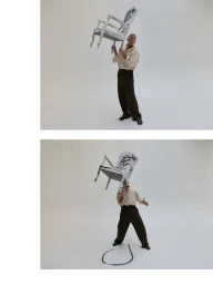 Vincent Cassel holding a painted wooden chair overhead against a white seamless background for Dear Vincent
