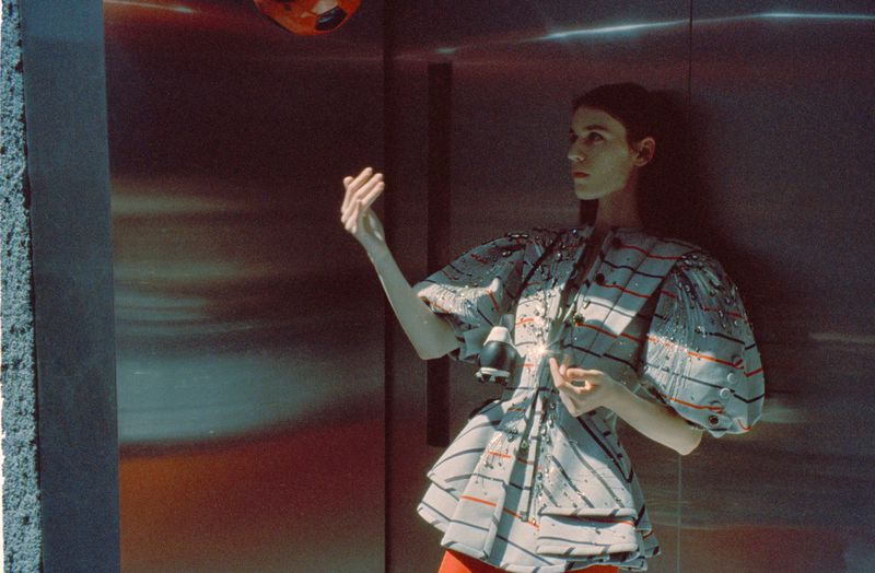 Woman in avant-garde fashion posing in a modern setting with a high-fashion aesthetic and unique artistic elements, capturing a creative mood.