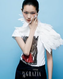 Model wearing a white graphic t-shirt with feather collar details against a solid blue background for Grazia China.