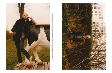Model Rianne Van Rompaey leaning against a decorative cow statue outdoors for Self Service magazine.