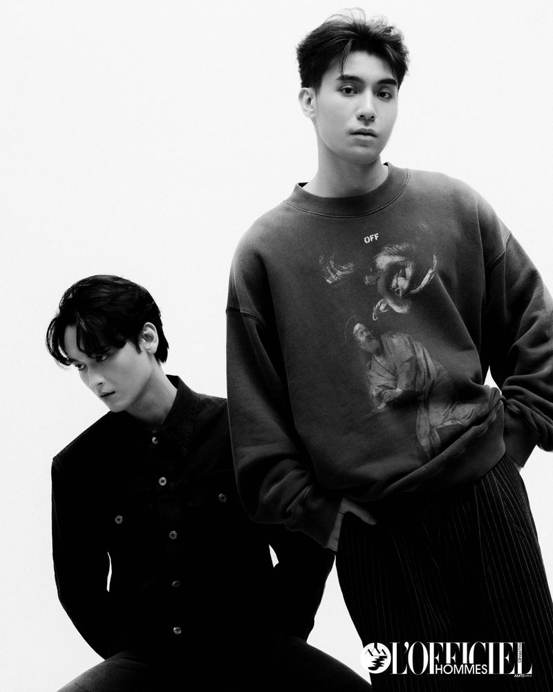Black and white portrait of two Asian men in a photo studio. One is wearing a sweatshirt and the other a suit jacket.