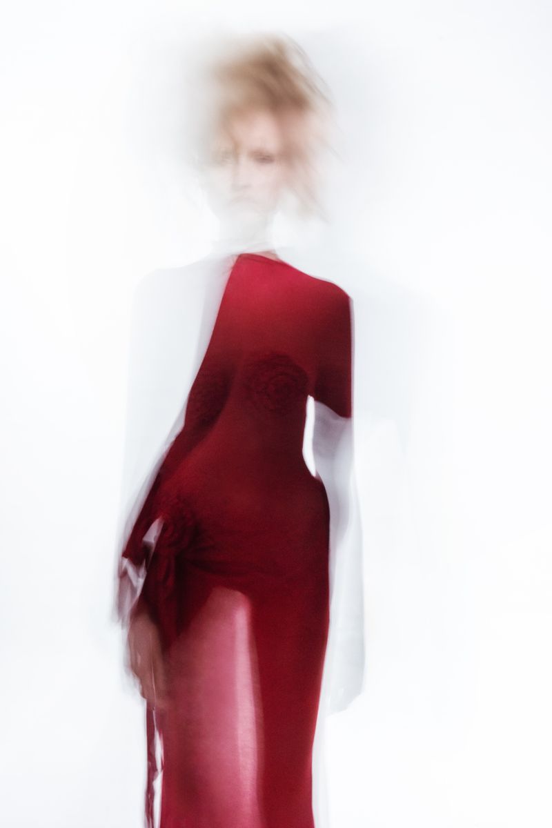 Abstract fashion portrait of a woman in a red dress, blurred motion and a white background combine for an ethereal, artistic effect.
