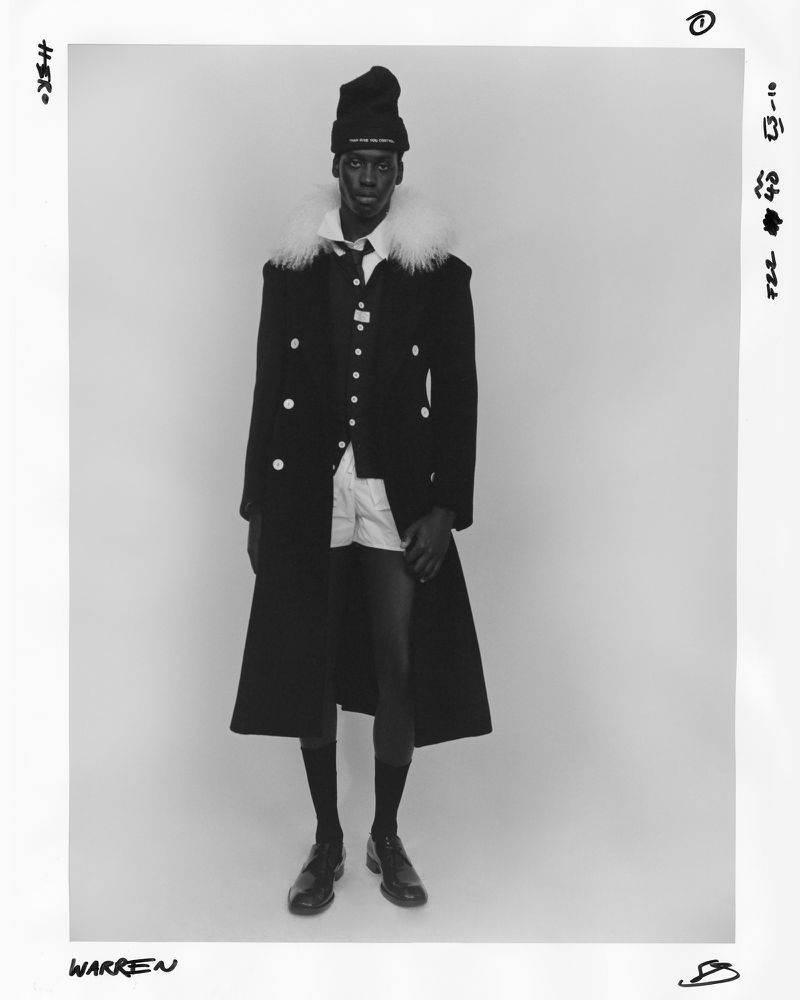 Black man wearing a black beanie coat and shorts against a white background for HERO Magazine.