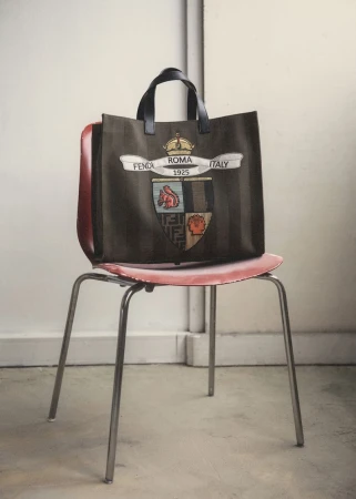 Fendi Roma Italy striped logo tote bag displayed on a red chair in a brightly lit interior, product shot for fashion.
