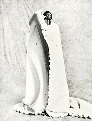 Model wrapped in a heavy white textured textile standing against a textured backdrop for HERO Magazine