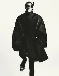 Model in black sculptural coat with blindfold against white background for HERO Magazine.