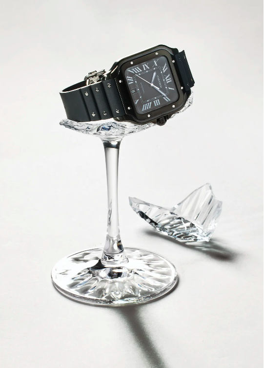 Black wristwatch displayed on broken crystal glass against a white backdrop in a studio setting. Ideal for luxury timepiece advertising.
