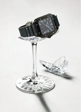 Black wristwatch displayed on broken crystal glass against a white backdrop in a studio setting. Ideal for luxury timepiece advertising.