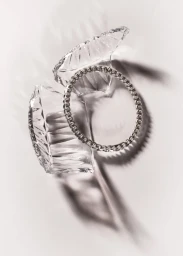Diamond tennis bracelet resting atop two shattered crystal fragments against a bright white background
