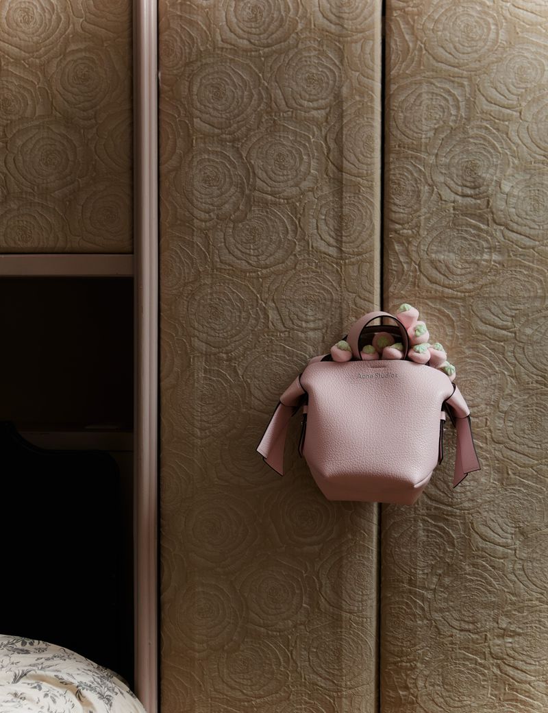 Designer handbag with floral accents against a textured wall. Close-up of a stylish accessory for fashion and personal style.