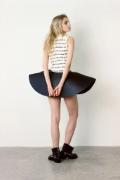 Model wearing printed top and structured black skirt against white seamless background in Heroine Magazine editorial.