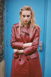 Model Annie Arnander wearing a red leather coat with arms crossed against a blue door for Heroine Magazine