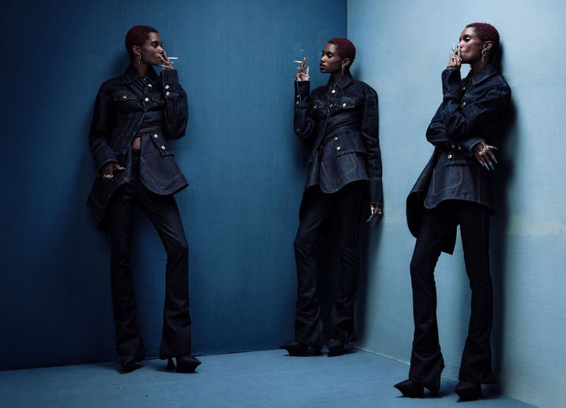 Three images of a woman with short hair and dark denim outfit smoking in front of a dark blue wall. Fashion shot, studio lighting.