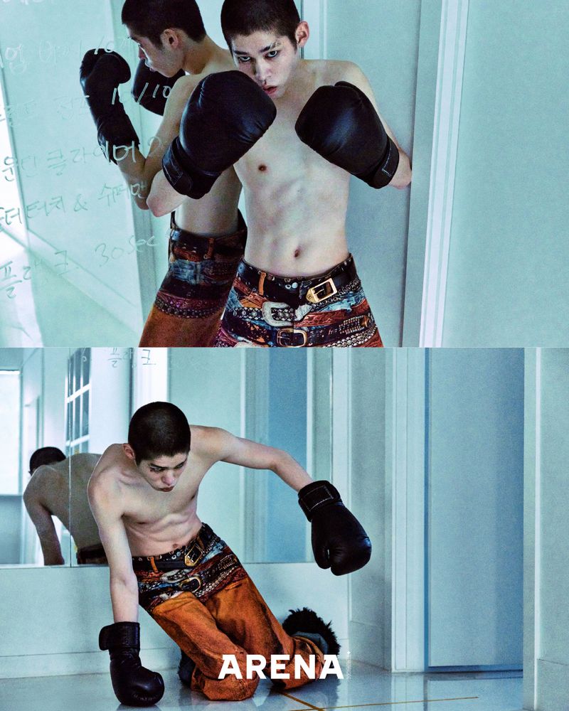 Shirtless Asian man in boxing gloves poses in front of a mirror in a fashion editorial, wearing patterned pants and looking intense.