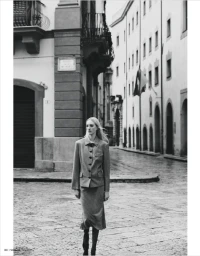 Model Ebba Bostrom walking on a cobblestone street in a skirt suit for Madame Germany, captured by Adriano Russo.