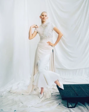 Model Bianca Balti posing in a white draped gown against a draped white fabric backdrop for Vanity Fair Italia