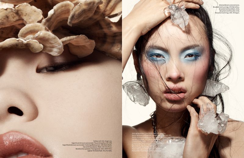 Beauty editorial shot of Asian woman with blue eyeshadow and decorative fungi. Close-up fashion shot in studio.