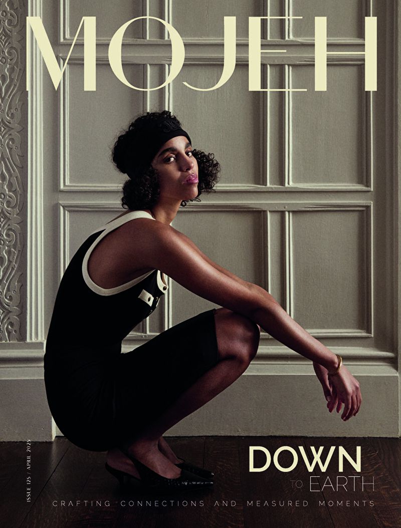 Model crouched wearing a black dress with white trim against a panelled wall for Mojeh Magazine