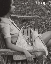 Model seated on a wooden park bench holding a woven handbag, shot in monochrome for Mojeh Magazine by Jonas Bresnan.