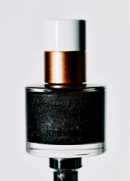 Close-up product shot of a dark shimmering nail polish bottle with a white and metallic cap against a seamless white background.