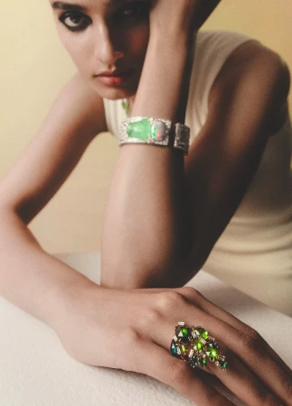 Model wearing statement green gemstone ring and cuff bracelet leaning on a surface