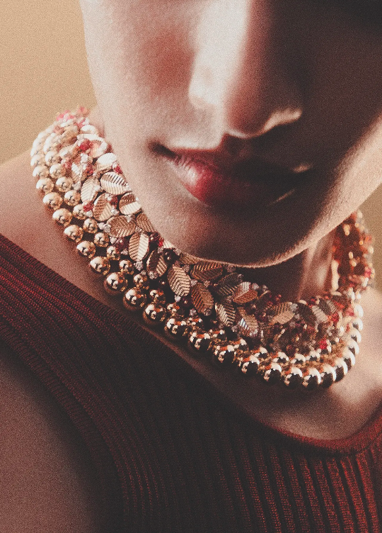 Close-up portrait of a model wearing a multi-strand gold leaf necklace and dark red ribbed top for Grazia Australia.
