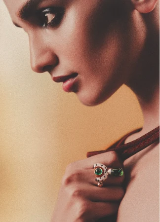 A woman's profile showcases a statement ring on her finger, close-up shot in a studio setting, against a soft yellow backdrop.