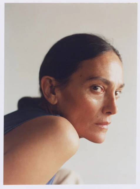 Close-up portrait of an adult woman looking over her shoulder in a photo studio with neutral tones and soft lighting.