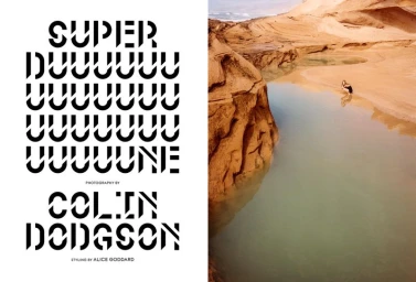 Editorial spread with stylized bold typography on the left and a desert landscape with a small figure near water on the right.