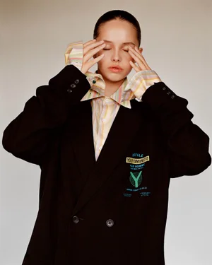 Model in oversized black blazer and striped shirt with hands near face for Middle Plane Magazine issue 10