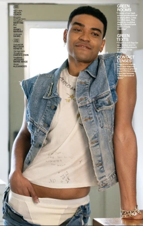 Stylish, youthful portrait of a mixed-race man indoors, wearing a denim vest and white graphic tee, showing off fashion-forward streetwear.