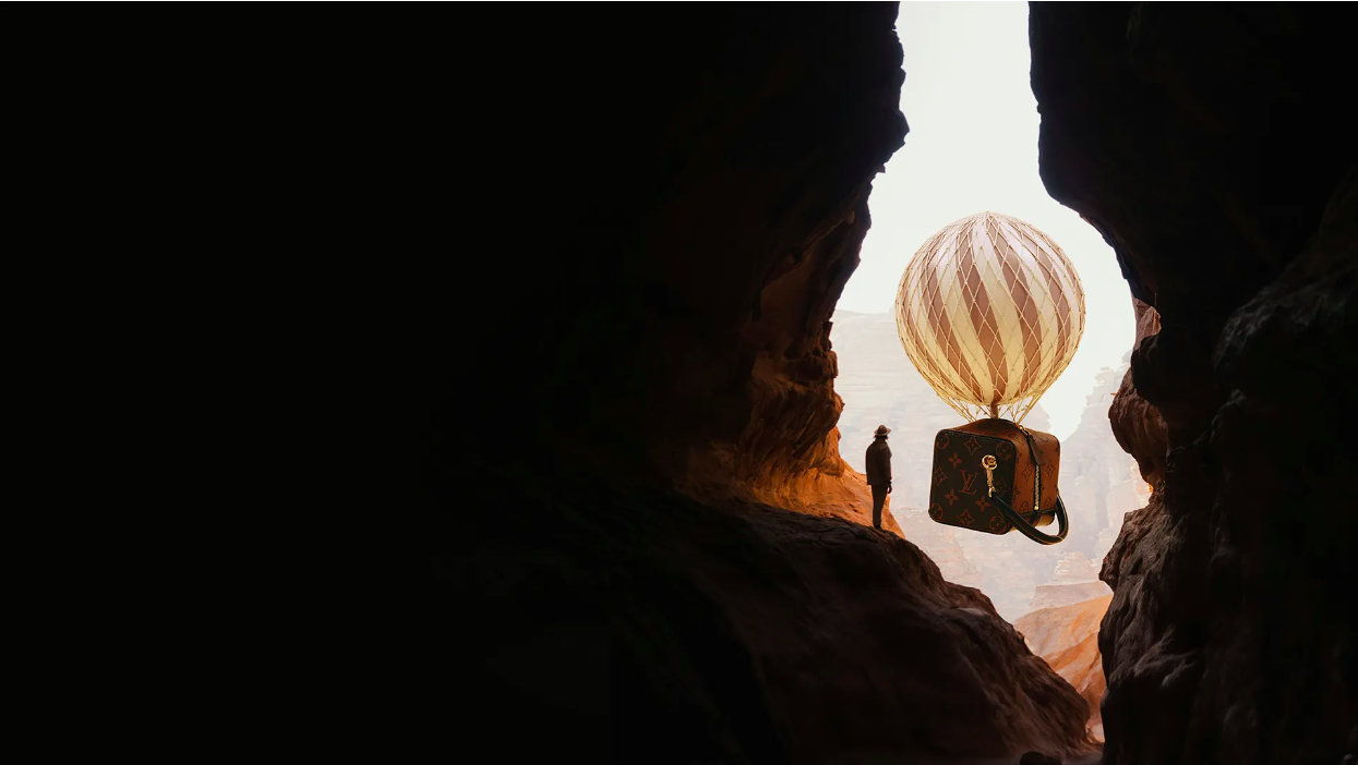 Whimsical image of hot air balloon crafted from a Louis Vuitton suitcase, floating above a silhouetted figure in a canyon setting.